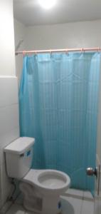 a bathroom with a toilet and a blue shower curtain at Your City•Home Apartment in Manila