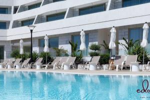 a row of lounge chairs next to a swimming pool at סוויטה משפחתית ליד הים - By Edomlux in Eilat