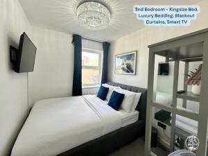 um quarto com uma cama com almofadas azuis e uma televisão em COASTAL RETREAT Town Centre Entire Property, Very Close to Sea & Restaurants, 2 King Size Beds em Porthcawl