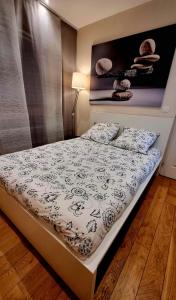 un letto con piumone bianco e nero in una camera da letto di Tranquillité a Vincennes