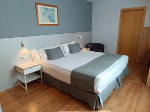 a hotel room with a large bed and a night stand at Mendez Nuñez Alicante in Alicante