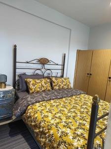 a bedroom with a bed with a yellow blanket and pillows at Polys Apartment and Paraskevi studio with view in Ptolemaida
