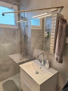 een badkamer met een wastafel, een douche en een spiegel bij Polys Apartment and Paraskevi studio with view in Ptolemaida