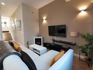Apartamento de Lujo - A 10 minutos del centro في مدريد: غرفة معيشة مع أريكة بيضاء ومدفأة