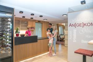 a man and woman holding a child in front of a counter at PEISERHOF ferien.wein.gut Südsteiermark in Wies