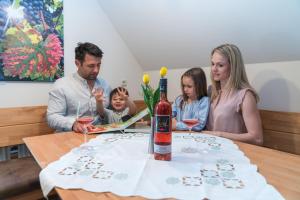 una famiglia seduta a un tavolo con una bottiglia di vino di PEISERHOF ferien.wein.gut Südsteiermark a Wies