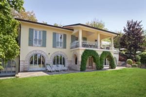 een groot huis met stoelen op een gazon bij Villa Ilaria with private pool and lake view in Torri del Benaco