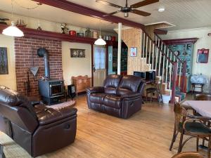 a living room with leather furniture and a fireplace at À la croisée des sommets in Notre-Dame-Des-Bois