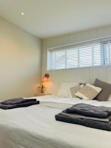 Un dormitorio con dos camas blancas y una ventana. en Villa de Duinfazant, en Bergen aan Zee