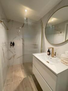 Un baño con ducha, lavabo y espejo. en Villa de Duinfazant, en Bergen aan Zee