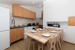 a kitchen with a wooden table with chairs and a kitchen with a white refrigerator at Casinha da Praia - Beachside Retreat Almoxarife in Praia do Almoxarife
