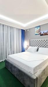 a large white bed in a room with white curtains at Jerusalem Hotel in Gitega