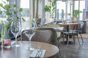 un restaurante con mesas y sillas y copas de vino en Hotel Noordzee, en Katwijk