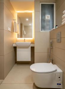 uma casa de banho com um WC, um lavatório e um espelho. em The Trios Hotel em Cochin