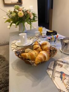 a table with a basket of croissants and a vase of flowers at Les Hortensias in Canly