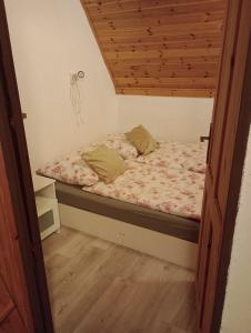 a bed in a small room with a wooden ceiling at Chata Žár in Žár