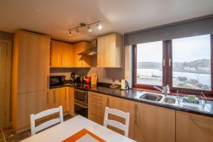 cocina con armarios de madera, fregadero y ventana en 4 Wheelhouse Apartment en Lochinver