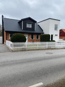 a house with a white fence next to a street at Svedala Malmö villa 7 bäddar in Svedala