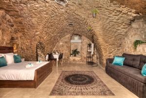 Cette chambre dispose d'un canapé et d'une table dans un mur en pierre. dans l'établissement קשתות - מתחם אבן בצפת העתיקה - Kshatot - Stone Complex in Old Tzfat, à Safed