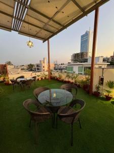 a patio with a glass table and chairs on the grass at Signature Boutique Hotel Karachi in Karachi