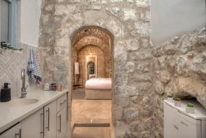 uma casa de banho com uma parede de pedra, um lavatório e uma banheira. em קשתות - מתחם אבן בצפת העתיקה - Kshatot - Stone Complex in Old Tzfat em Safed