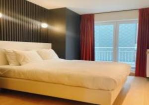 een slaapkamer met een wit bed en een groot raam bij Manon Knokke - appartement met zeezicht aan het Rubensplein in Knokke-Heist
