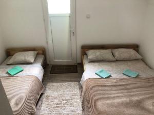 Private accommodation Kalezić في مويكوفاتش: سريرين في غرفة صغيرة عليها وسائد خضراء