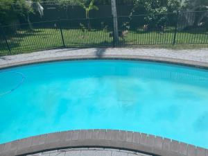 a swimming pool with blue water in a fence at Spacious studio unit in Rochedale South