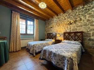 a bedroom with two beds and a stone wall at Casa Rural La Socarrena in Luzmela