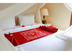 a white bed with a red blanket on it at Gongwi Cottages Sidemen in Sidemen