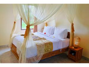 a bedroom with a bed with white sheets and a window at Gongwi Cottages Sidemen in Sidemen