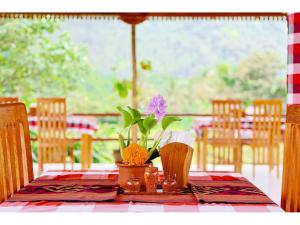 a table with a purple flower in a vase on it at Gongwi Cottages Sidemen in Sidemen