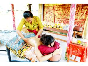 two women are sitting on beds and one is getting a massage at Gongwi Cottages Sidemen in Sidemen