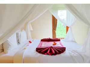 a white bed with red sheets and flowers on it at Gongwi Cottages Sidemen in Sidemen