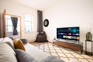 ein Wohnzimmer mit einem Sofa und einem Flachbild-TV in der Unterkunft Ko-Living Space an der Oper - Street Art Design Apartments in Halle an der Saale