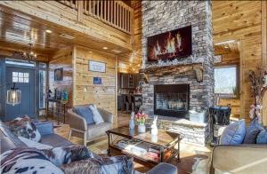 a living room with a stone fireplace and a tv at Hawk’s View Log Cabin -Mountains in Gatlinburg. in Gatlinburg