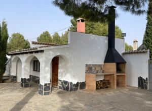 ein weißes Haus mit einem Kamin im Innenhof in der Unterkunft Villa privada piscina-tenis in Villarrobledo