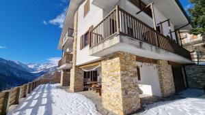 a building with a balcony with snow on the ground at La Misun de Ciafrè in Casteldelfino