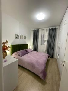 a bedroom with a bed with a purple blanket at Access apartment in Tirana