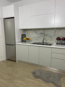 a kitchen with white cabinets and a sink and a refrigerator at Access apartment in Tirana