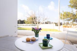 einen weißen Tisch mit zwei Tassen und Muffins drauf. in der Unterkunft Smilax - Hydruntum Holiday Rooms in Otranto