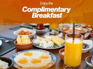 una mesa con platos de desayuno y un vaso de zumo de naranja en A One Hotel Clifton en Karachi