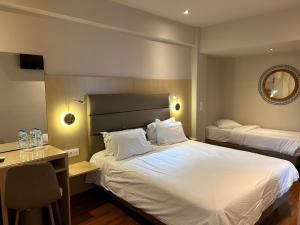 1 dormitorio con 2 camas, escritorio y espejo en Anemoni Piraeus Hotel, en Pireo