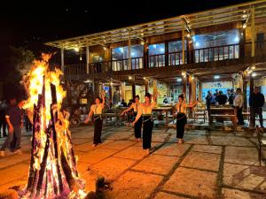 a group of people dancing around a fire at Na Thẩm Eco Hill Homestay - Trạm Tấu in Cham Ta Lao