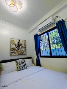 a bedroom with a bed and a window with blue curtains at MP Apartments Leyte in Hindang