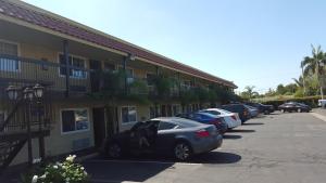 Anaheim Astoria Inn & Suites في أنهايم: صف من السيارات تقف في موقف للسيارات بجوار مبنى