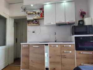 a kitchen with white cabinets and a microwave at APARTMANI Emerald Dream in Novi Sad