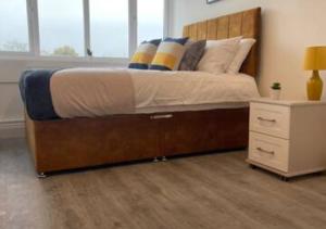 a bed with a wooden frame and a night stand at Flitwick Luxury Apartment in Flitwick