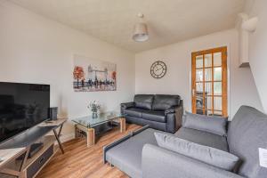 a living room with a couch and a tv at Immaculate Two Bedroom House with Parking in Bedford