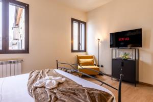 a bedroom with a bed and a tv and a chair at Certosa Charme 10 Minuti da SAN SIRO e RHO FIERA in Milan
